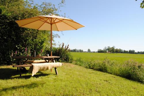 a picnic table with an umbrella next to a field at Vakantie Appartement Klavertje 4 in Laren Gld in Laren