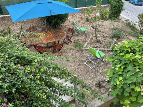 appartement nice في نيس: طاولة وكراسي ومظلة في حديقة