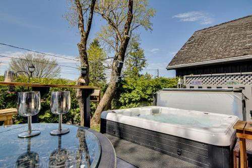a hot tub on a patio with two glasses on a table at Le petit Manoir Spa et Vue sur rivière St Maurice in Grandes-Piles