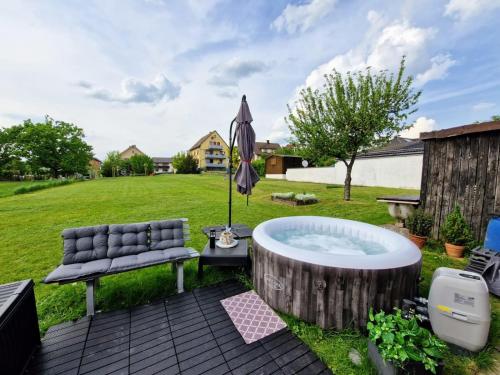 RödentalにあるFerienhaus Anni Rödentalのベンチとパラソル付きの庭のホットタブを利用できます。