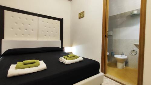 ポルト・チェザーレオにあるBed Anthos Porto Cesareoの黒いベッド1台、タオル、バスルームが備わります。