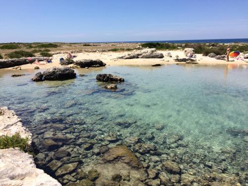 a beach with rocks and water and people on the beach at Porto Cesareo Sant'Isidoro Delizioso Trilo in Sant'Isidoro