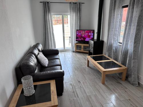 a living room with a leather couch and a tv at Casa Maria João in Lagos