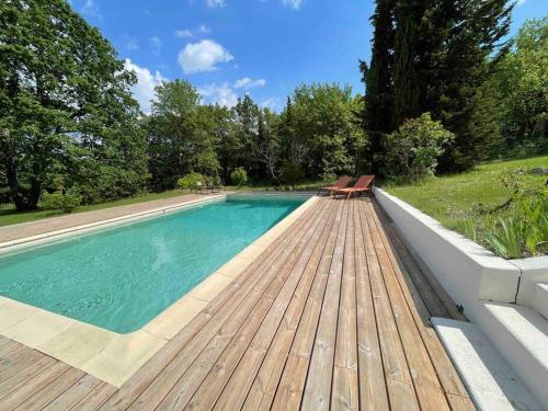 una piscina con due panche su una terrazza di legno di Mas de la Pivoine a Le Puy-Sainte-Réparade