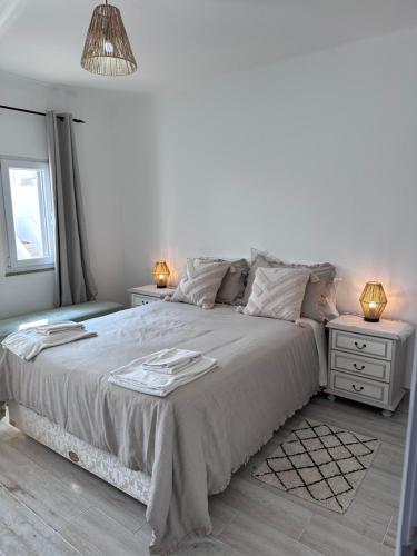 a white bedroom with a large bed and two night stands at Casa Maria João in Lagos