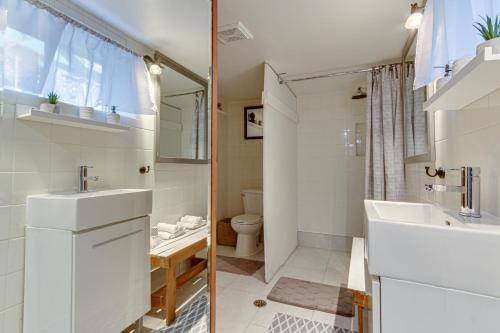 a white bathroom with a sink and a toilet at Le petit Manoir Spa et Vue sur rivière St Maurice in Grandes-Piles