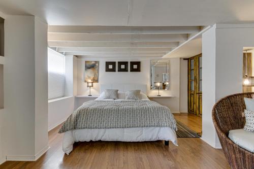 a bedroom with a large bed and a chair at Le petit Manoir Spa et Vue sur rivière St Maurice in Grandes-Piles