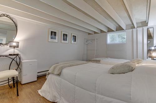 a white bedroom with two beds and a mirror at Le petit Manoir Spa et Vue sur rivière St Maurice in Grandes-Piles