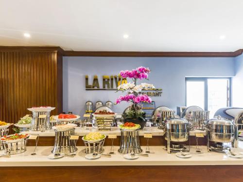 a buffet line with flowers and plates of food at IBIZA Riverfront Da Nang Hotel in Da Nang