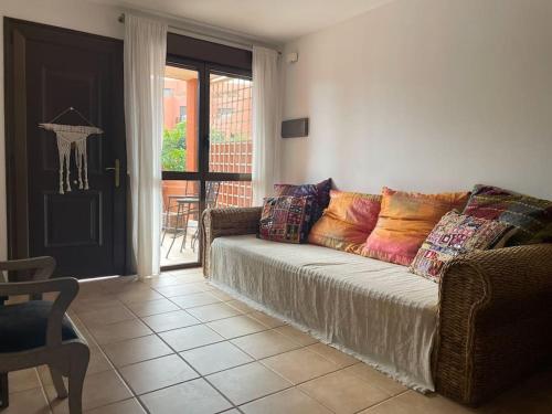 Cozy apartment with large terrace next to the pool في La Tejita: غرفة معيشة مع أريكة ومخدات ملونة عليها