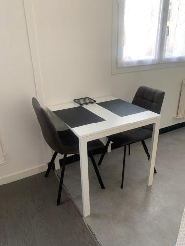 une table blanche et deux chaises dans une pièce dans l'établissement Location 2 pers centre historique de quimper, à Quimper