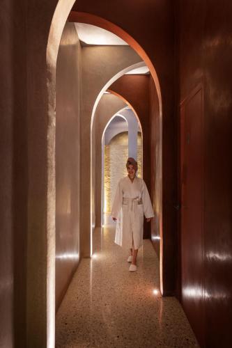 a woman walking down a hallway in a building at 72 Hotel & Spa in Marrakech
