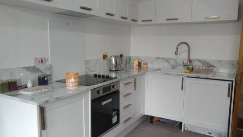 a kitchen with white cabinets and a stove top oven at Dunoon Gourock Inverkip Apartment in Gourock