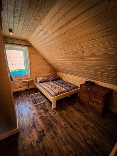 an attic room with a bed and a window at Chata Tołhaja in Polańczyk