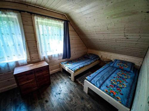 una camera con due letti in una cabina di legno di Chata Tołhaja a Polańczyk