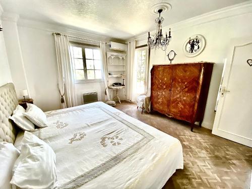 a bedroom with a large white bed with a chandelier at Villa Daurus in Vallauris