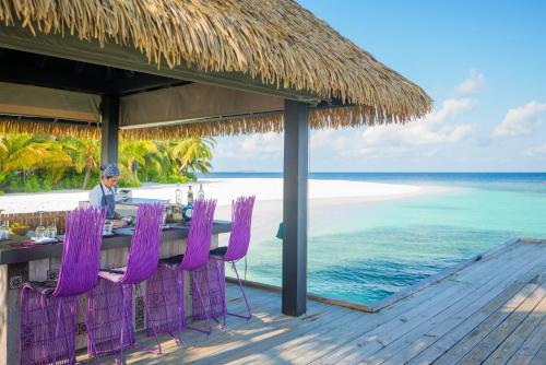 a man sitting at a table on the beach at Kandolhu Maldives in Himandhoo 