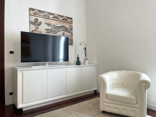 a living room with a tv on a white cabinet and a chair at VILLA EUGENIA - Luxury Flat in the Centre, with Parking Space in Bordighera