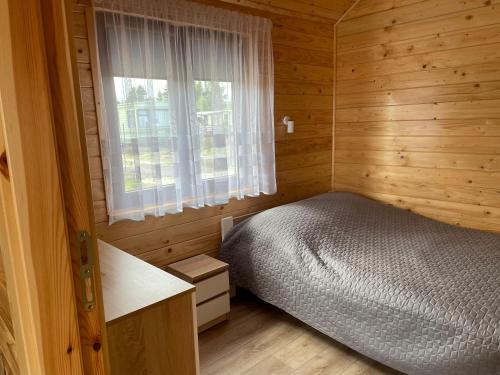 a bedroom with a bed in a wooden cabin at Uroczy Zakątek 2 in Chłopy