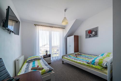 a bedroom with two beds and a tv in it at Pod Jedynkami in Władysławowo