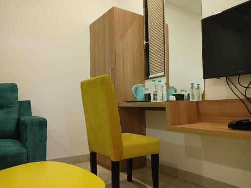 a yellow chair sitting next to a desk with a tv at Hotel New Centro in Gulbarga