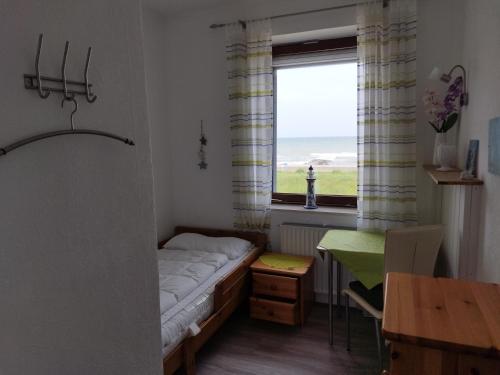 Schlafzimmer mit einem Bett, einem Tisch und einem Fenster in der Unterkunft Ferienwohnung mit Meerblick in Dahme