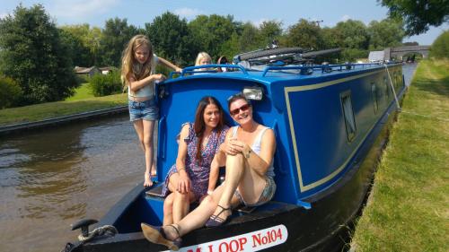 Trzy dziewczyny siedzące na niebieskiej łodzi w obiekcie Narrowboat canal holiday from19th august w mieście Aldermaston
