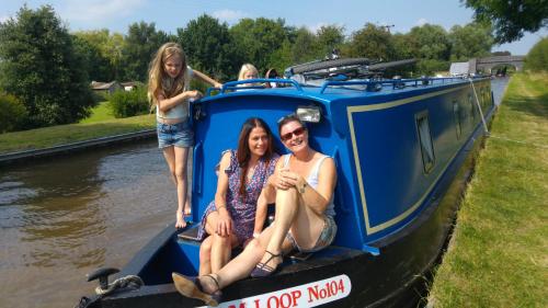 three girls sitting on the back of a blue boat at Narrowboat canal holiday from19th august in Aldermaston