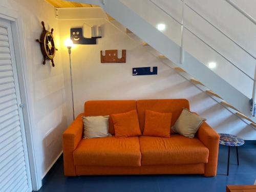 an orange couch in a room with a staircase at Casa Nadip in Ustica