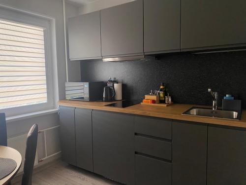 eine Küche mit grauen Schränken, einer Spüle und einem Fenster in der Unterkunft DAK apartament in Ventspils