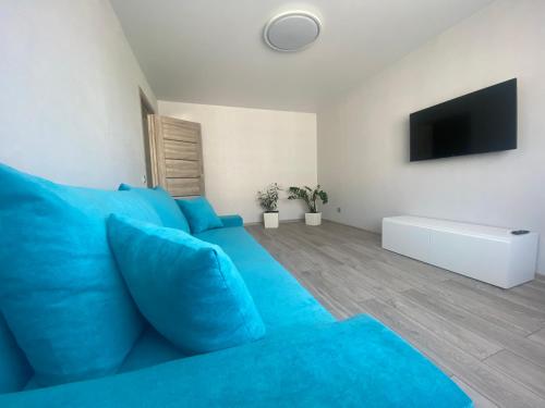 eine blaue Couch in einem weißen Wohnzimmer in der Unterkunft DAK apartament in Ventspils