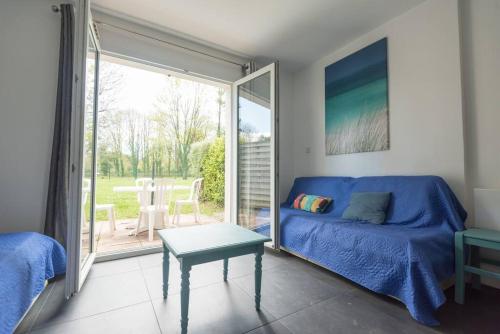 a living room with a blue couch and a sliding glass door at Maison au calme à l'intérieur du golf de Ploëmel, entre terre et mer, 2 chambres, 10 min des plages in Ploemel