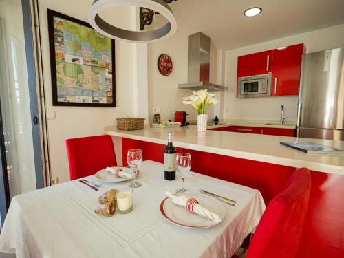 タリファにあるLankarifa Apartmentのキッチン(テーブル、赤い椅子、白いテーブルクロス付)