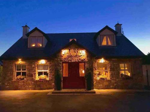 a stone house with lights on it at night at Cosy Rooms in a Stone Cottage in Galway
