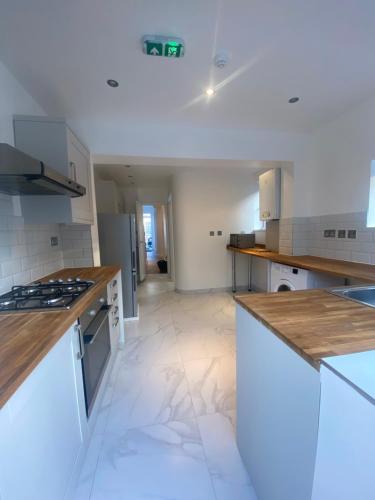 a large kitchen with white appliances and wooden counter tops at Cosy house in Newham in London
