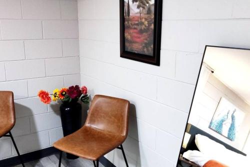 a room with two chairs and a mirror and flowers at Spacious Suite Close to Downtown Indy/ King Bed in Indianapolis