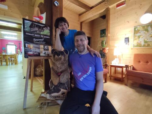 a man and a woman sitting next to a teddy bear at Chalet Rosa dei Monti in Valprato Soana