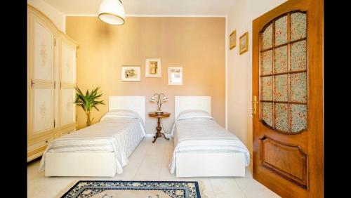 two beds in a room with a door at B&B Maison Rosetta IUN-E4948 in Nuoro