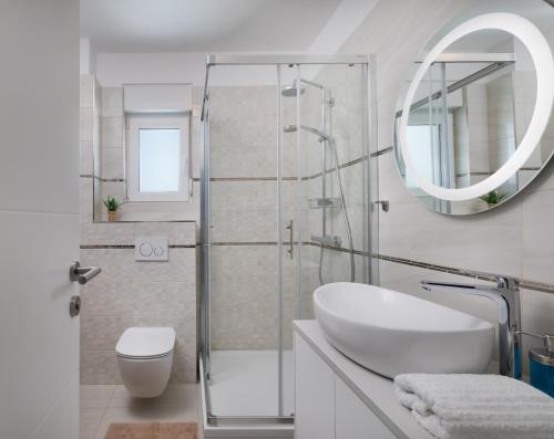 ein weißes Badezimmer mit einem Waschbecken und einem Spiegel in der Unterkunft Villa Sunset Bay - amazing view and large heated pool in Ljubač