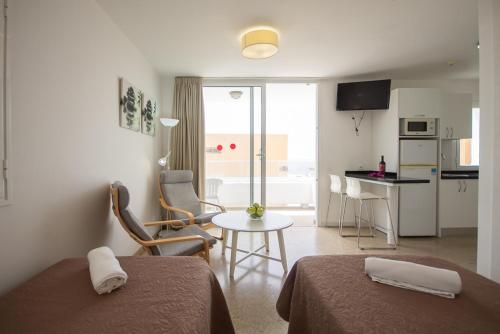 a hotel room with two beds and a table and a kitchen at Apartamentos Tarahal in San Agustin