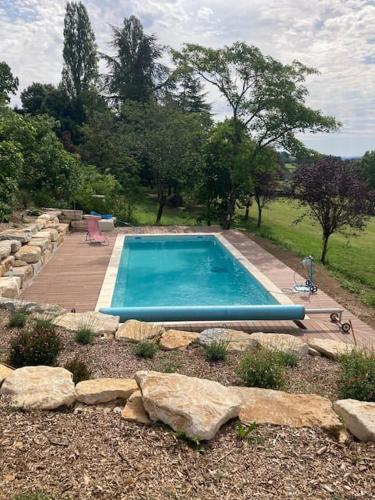une piscine au milieu d'un jardin avec des rochers dans l'établissement Cabane du Canada, à Azerat