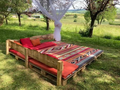 ein Holzbett mit roten Kissen auf einem Feld in der Unterkunft Cabane du Canada in Azerat