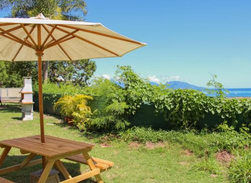 une table en bois avec un parasol dans l'herbe dans l'établissement Temana Airport Faa'a,Tahiti, à Fa'a'ā