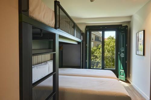 a bedroom with two bunk beds and a window at LATROUPE Prado Hostel in Madrid