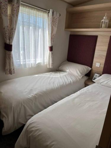 2 łóżka w sypialni z oknem w obiekcie New Forest Retreat on a 5* Holiday Resort w mieście New Milton