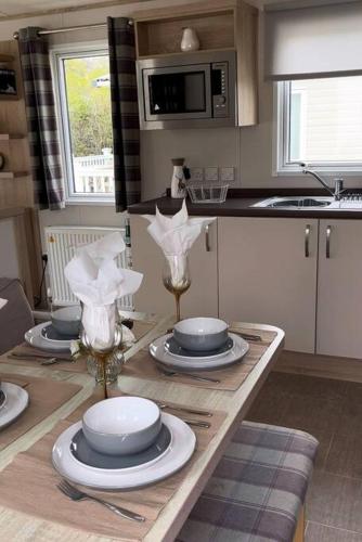 a kitchen with a table with plates and wine glasses at New Forest Retreat on a 5* Holiday Resort in New Milton