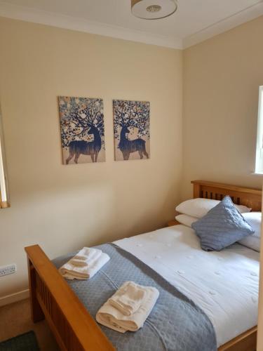 a bedroom with a bed with two pictures on the wall at 1 Golf Mews in Ballater