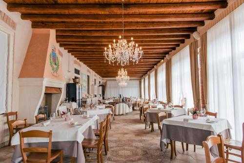 a restaurant with white tables and chairs and a chandelier at Fracanzana Hotel in Montebello Vicentino