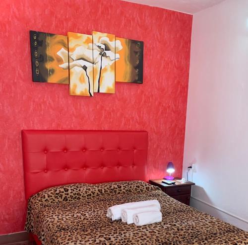 1 dormitorio rojo con cabecero rojo y 3 cuadros en la pared en Cassanova II en San Luis