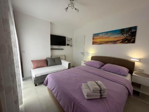 a bedroom with a purple bed and a couch at Apartments Ostojic in Krk
